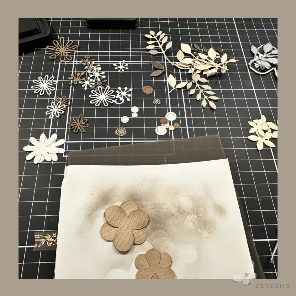 this is a picture of all the flower and foliage die cuts waiting their turn to have tim holtz distress ink in scorched timber added to their edges to make them looked aged.